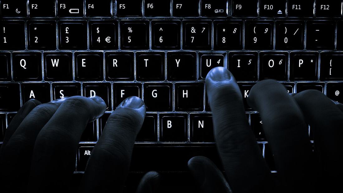 Hände an einer beleuchteten Tastatur